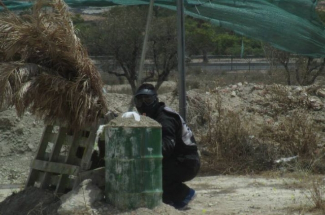  boy behind a green barrel 